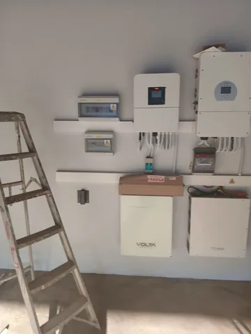 Solar inverters, Volta batteries and combiner boxes mounted on a utility-room wall
