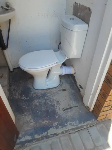 Newly installed white toilet and basin plumbing in a utility bathroom