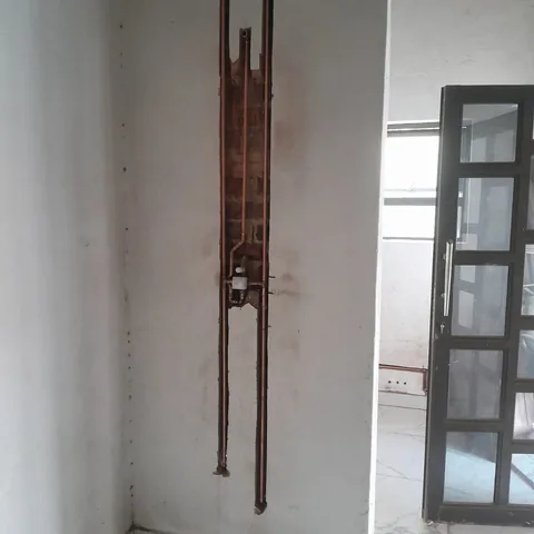 Plumbing rough-in with copper pipes and a valve box in an open wall chase